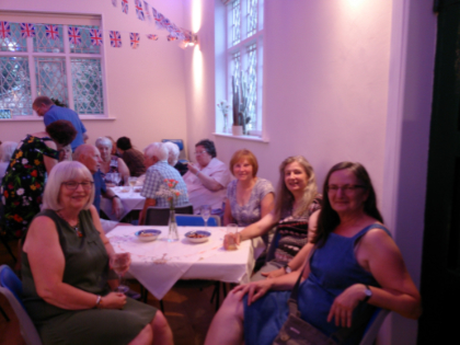 Photo of people seated at a table and smiling, inside the Old School Room hall building, Cossall